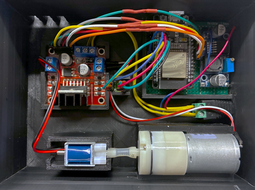 Inside the printed cuff enclosure: a motor driver board and an ESP32 on a prototyping board wired to a solenoid valve and a diaphragm air pump seated in printed brackets.
