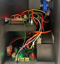 Inside the pump enclosure: a microcontroller board on a standoff rail above a bank of colour-coded terminal blocks, with looms running down to the components below.