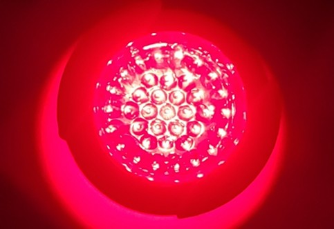 The LED source array running, individual emitters visible through the lens optic against saturated red illumination.