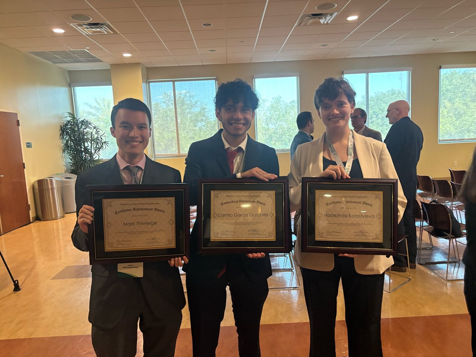 Three of us standing side by side, each holding a framed certificate.